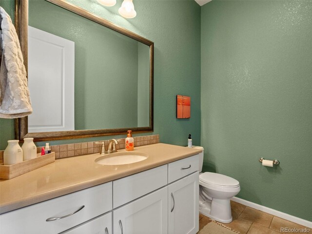 bathroom with vanity, toilet, tile patterned flooring, and baseboards