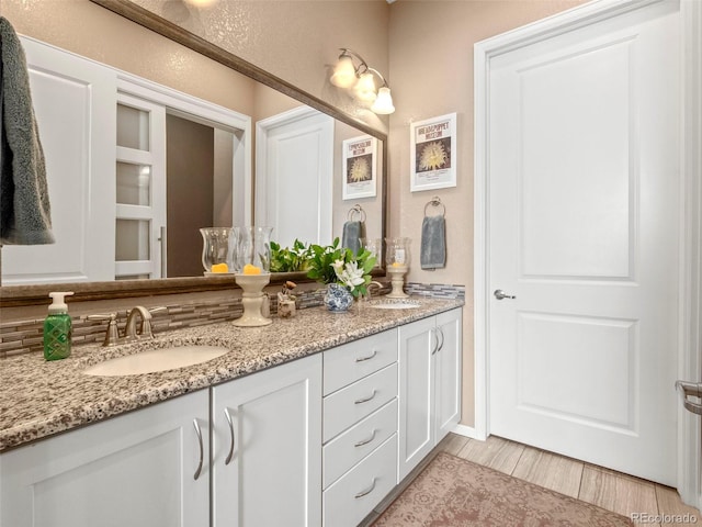 full bath with double vanity and wood finished floors