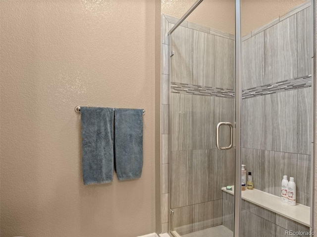 bathroom with a textured wall and a shower stall