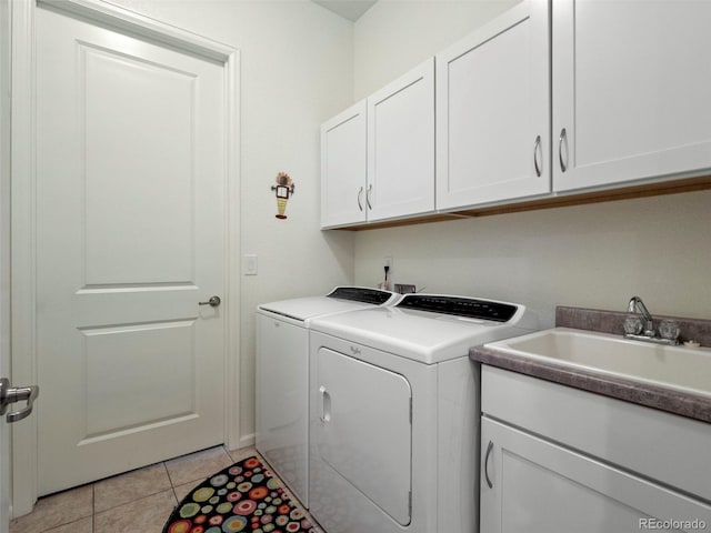 laundry room with washer and clothes dryer, cabinet space, and light tile patterned floors