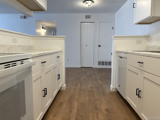 kitchen with stove, dark wood-style floors, white dishwasher, a textured ceiling, and white cabinets