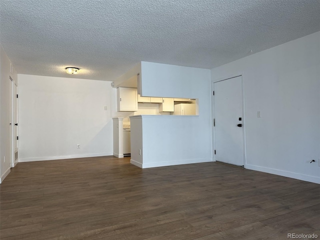 unfurnished living room with dark wood finished floors, a textured ceiling, and baseboards
