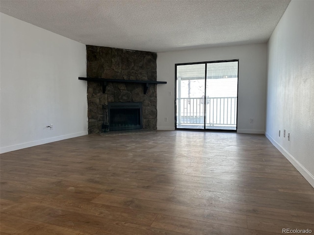 unfurnished living room featuring dark wood-type flooring, a textured ceiling, a fireplace, and baseboards