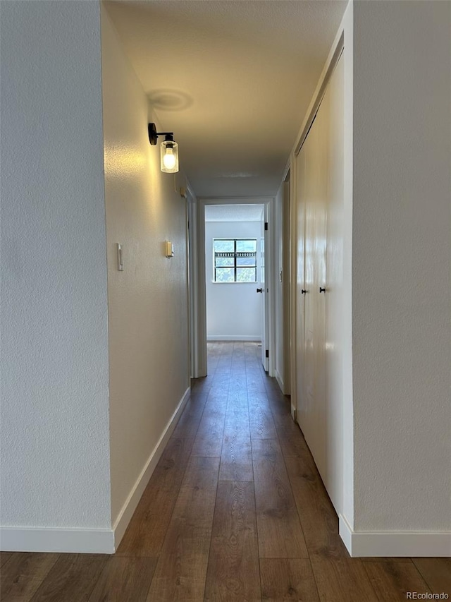 hall featuring dark wood-type flooring and baseboards