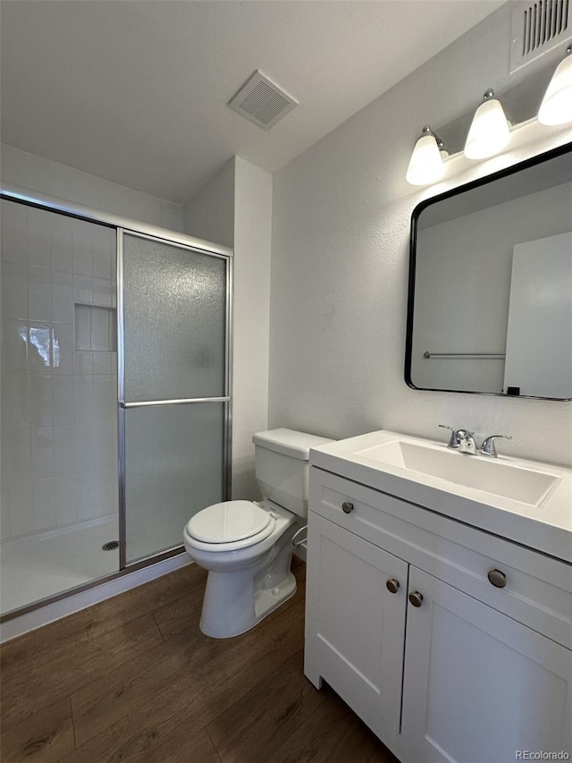 full bath featuring wood finished floors, toilet, a stall shower, and vanity