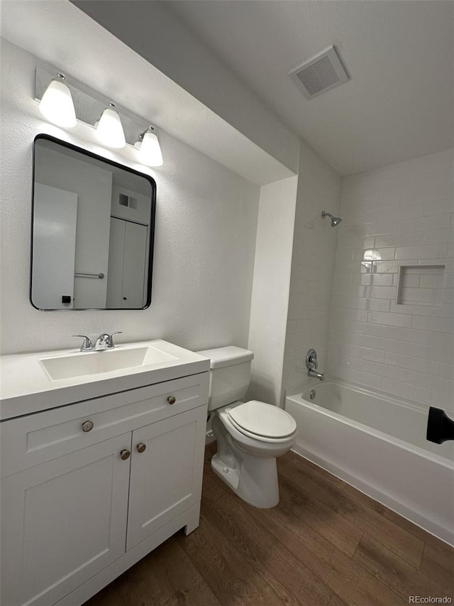 full bathroom featuring wood finished floors, toilet, vanity, and bathtub / shower combination