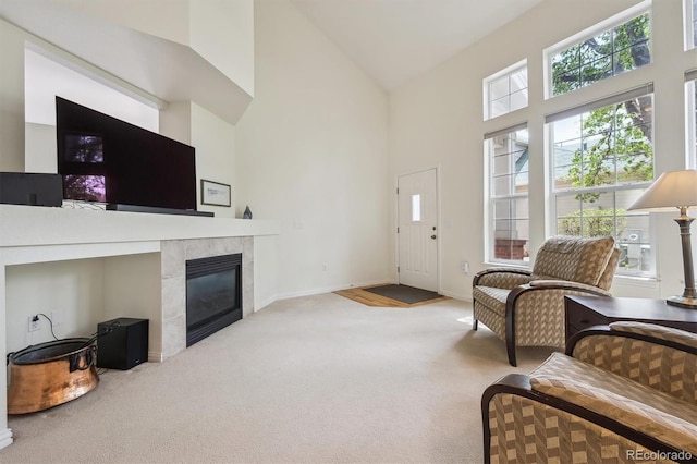 carpeted living area with plenty of natural light, baseboards, a tiled fireplace, and high vaulted ceiling