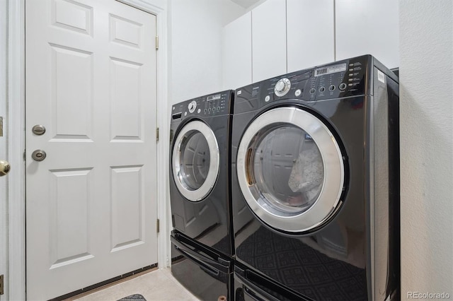washroom with washer and dryer, light tile patterned floors, and cabinet space