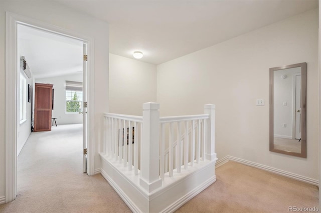 hall featuring baseboards, carpet flooring, and an upstairs landing