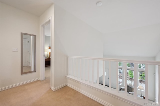 corridor featuring carpet floors, baseboards, and vaulted ceiling