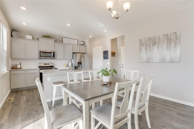 dining space with light wood-style flooring, baseboards, a chandelier, and recessed lighting