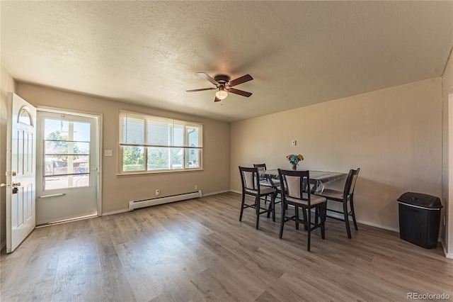 dining room featuring ceiling fan, a baseboard radiator, hardwood / wood-style floors, and a textured ceiling