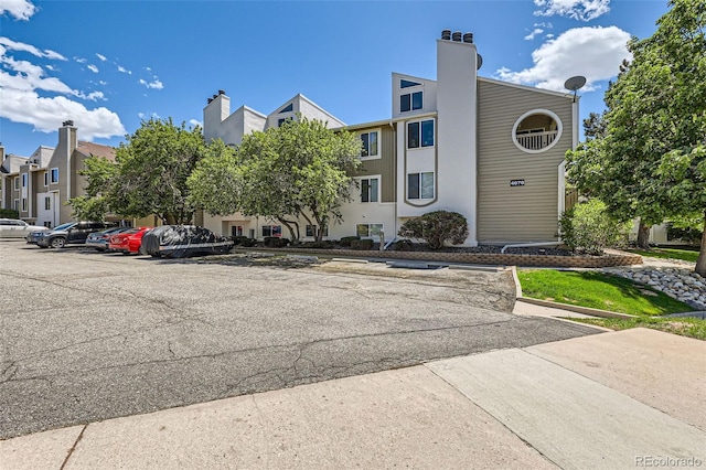 view of building exterior featuring uncovered parking and a residential view