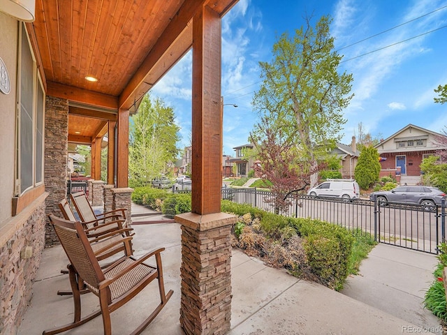 view of patio / terrace with fence, a porch, and a residential view