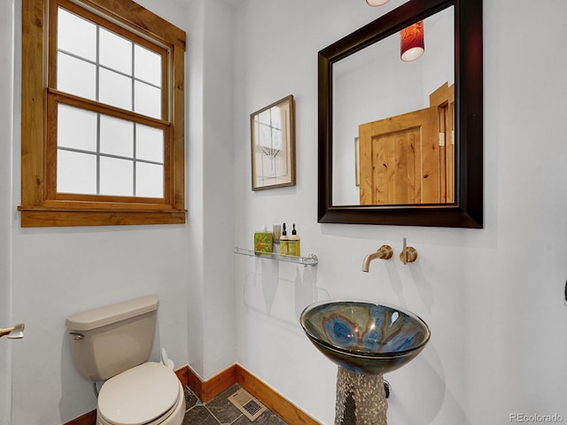 bathroom with a sink, baseboards, toilet, and visible vents