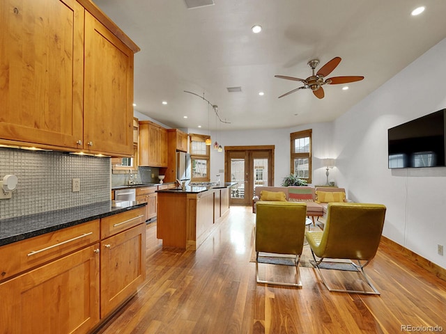 kitchen with a sink, light wood-style flooring, ceiling fan, and tasteful backsplash