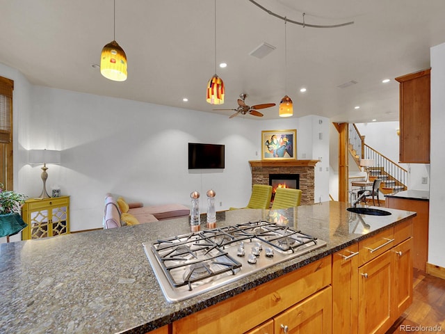 kitchen with open floor plan, a sink, stainless steel gas stovetop, and dark wood-type flooring