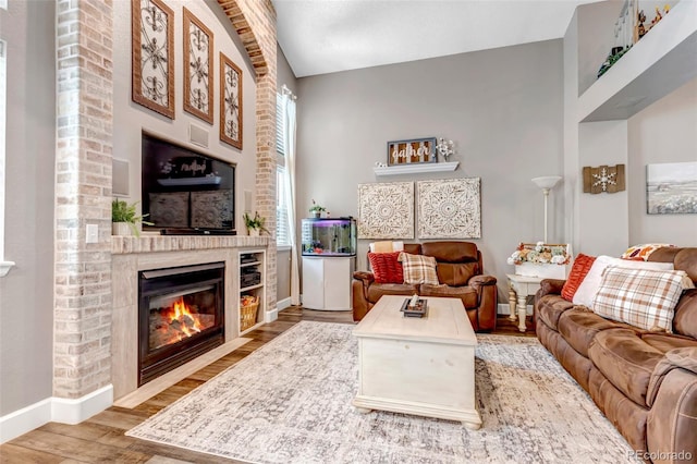 living room with hardwood / wood-style floors, lofted ceiling, and a fireplace