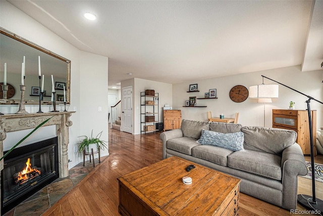 living area featuring a fireplace with flush hearth, recessed lighting, stairs, and wood finished floors