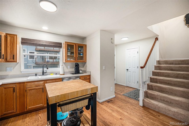 kitchen featuring light wood-type flooring, a sink, brown cabinets, and light countertops