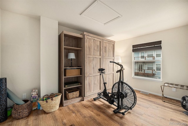 workout area with baseboards, visible vents, and light wood-type flooring