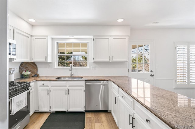 7193 S Newport Way, Centennial, CO 80112 - kitchen featuring appliances with stainless steel finishes, light stone counters, white cabinets, light wood-type flooring, and recessed lighting
