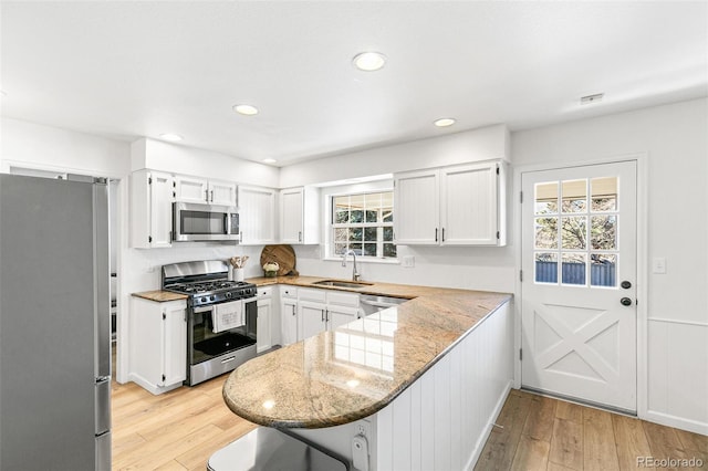 7193 S Newport Way, Centennial, CO 80112 - kitchen featuring stainless steel appliances, a peninsula, white cabinetry, light wood-style flooring, and recessed lighting
