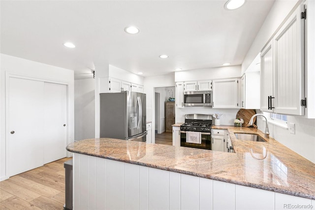 7193 S Newport Way, Centennial, CO 80112 - kitchen featuring appliances with stainless steel finishes, light stone countertops, recessed lighting, a peninsula, and light wood finished floors