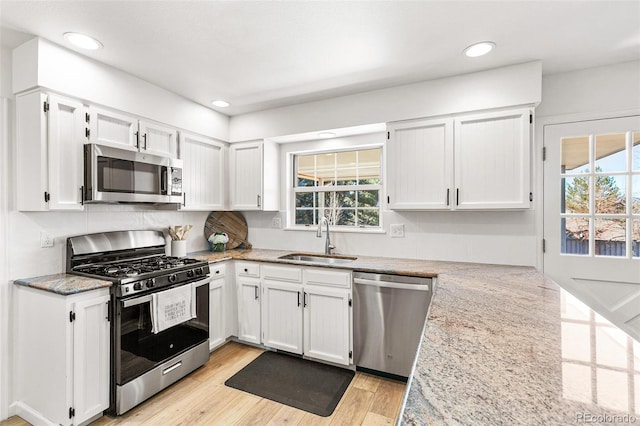 7193 S Newport Way, Centennial, CO 80112 - kitchen featuring stainless steel appliances, white cabinetry, light stone counters, light wood finished floors, and recessed lighting