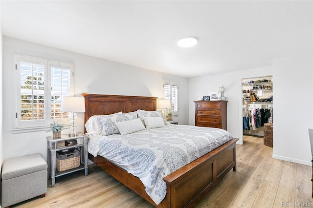 7193 S Newport Way, Centennial, CO 80112 - bedroom featuring multiple windows, light wood finished floors, a closet, and a walk in closet