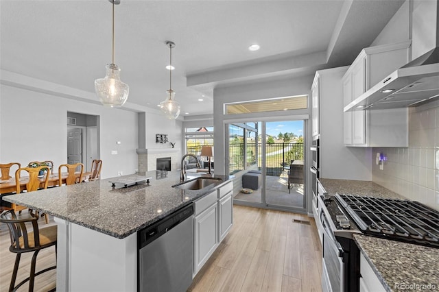 kitchen with stainless steel appliances, sink, an island with sink, and white cabinets