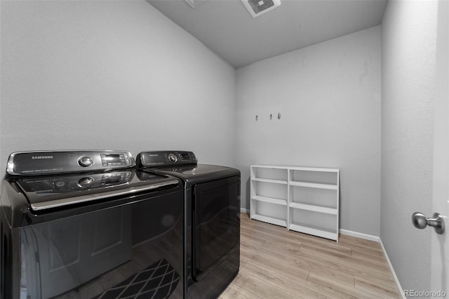 washroom with light hardwood / wood-style flooring and washing machine and clothes dryer