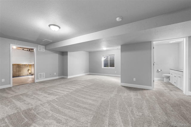 basement with a textured ceiling and light colored carpet