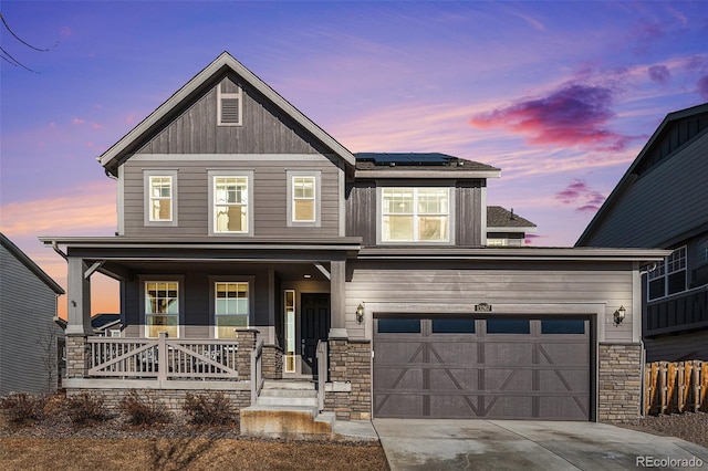 craftsman house featuring a garage, covered porch, and solar panels