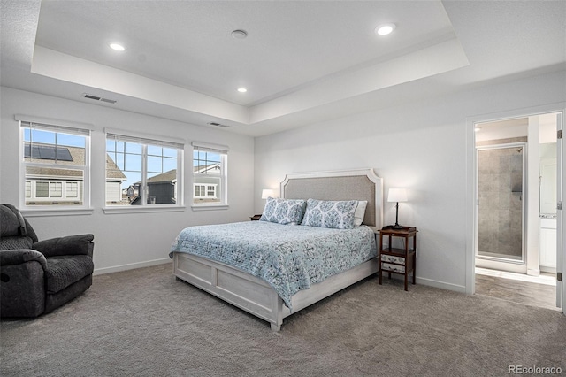 bedroom featuring a tray ceiling, ensuite bath, and carpet flooring