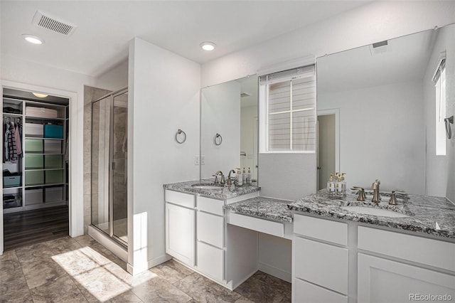 bathroom featuring a shower with shower door and vanity