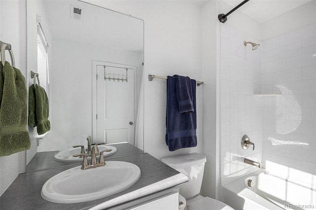 full bathroom with tiled shower / bath combo, vanity, and toilet