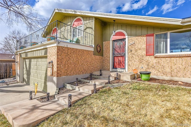 view of exterior entry featuring a balcony, a garage, brick siding, fence, and driveway