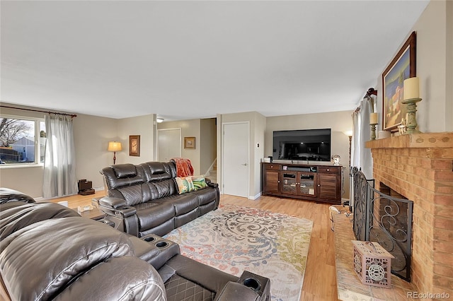 living area featuring light wood-type flooring, a brick fireplace, and stairway