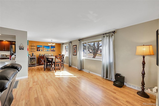 dining area with a notable chandelier, light wood-style flooring, visible vents, and baseboards