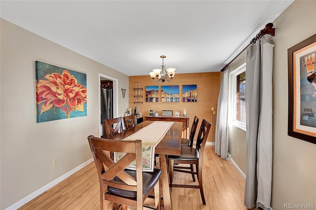 dining room featuring light wood finished floors, baseboards, and a chandelier