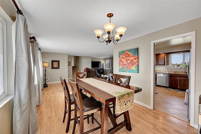 dining space with baseboards, light wood-style flooring, stairway, and a notable chandelier