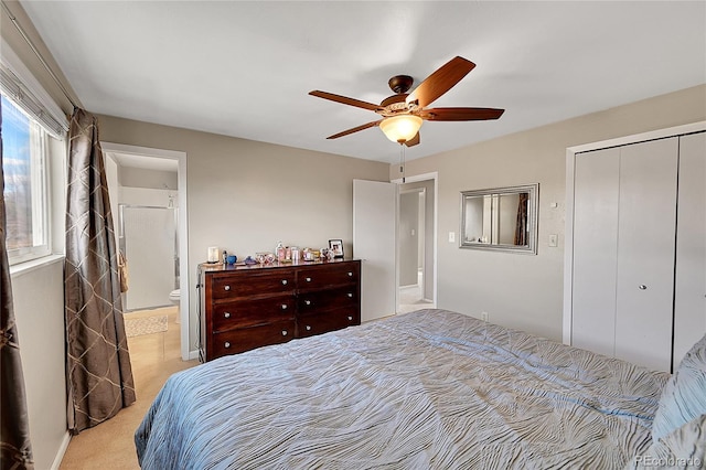 bedroom featuring light carpet, a closet, connected bathroom, and a ceiling fan