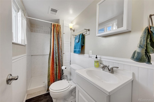 bathroom with visible vents, toilet, a wainscoted wall, vanity, and a shower stall