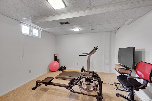 exercise room with a paneled ceiling, carpet flooring, visible vents, and baseboards