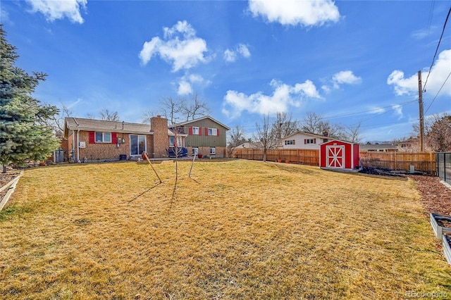 view of yard featuring an outbuilding, a storage unit, and a fenced backyard