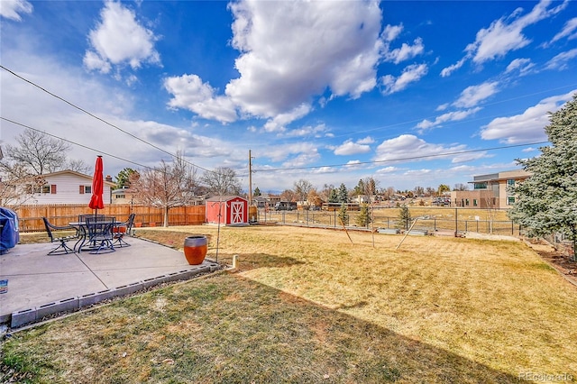 view of yard featuring a storage shed, a fenced backyard, an outdoor structure, and a patio