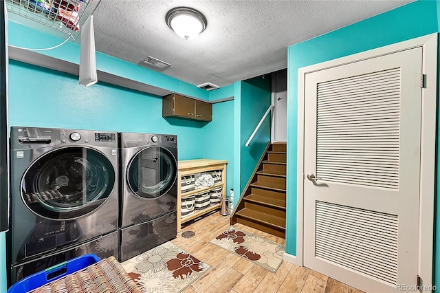 laundry area with cabinet space, visible vents, wood finished floors, independent washer and dryer, and a textured ceiling