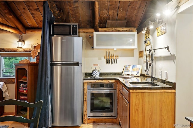 1634 Caribou Rd, Nederland, CO 80466 - kitchen with appliances with stainless steel finishes, a wood ceiling with exposed beams, brown cabinets, dark countertops, and wood finished floors