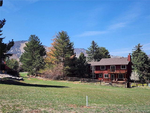 view of yard featuring a mountain view, fence, and a balcony